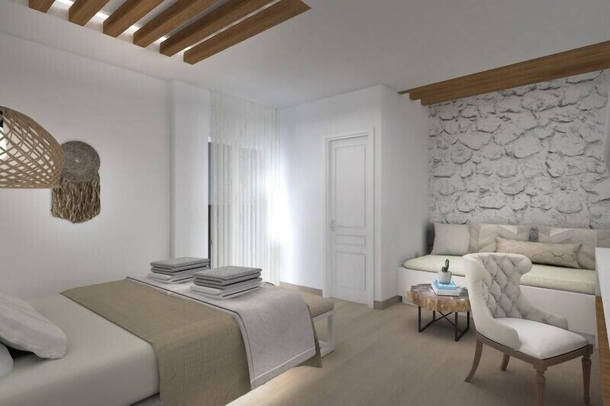 A modern bedroom with a bed, a sofa, a chair, and a stone wall.