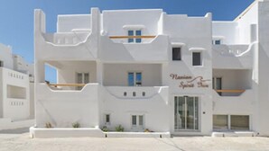Un edificio blanco con balcones y un cartel que dice "Naxos Spirit Inn".