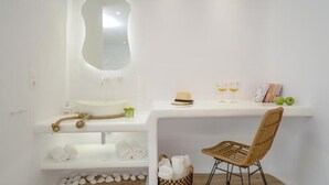 Un baño minimalista con un espejo grande, un lavabo y un mueble de tocador con toallas y artículos de aseo.