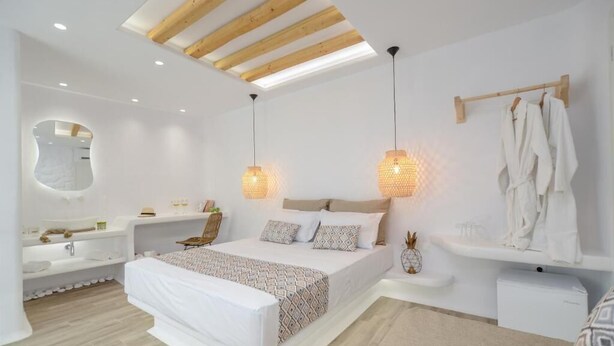 Un dormitorio moderno con una cama grande, una bañera integrada y techo de madera.