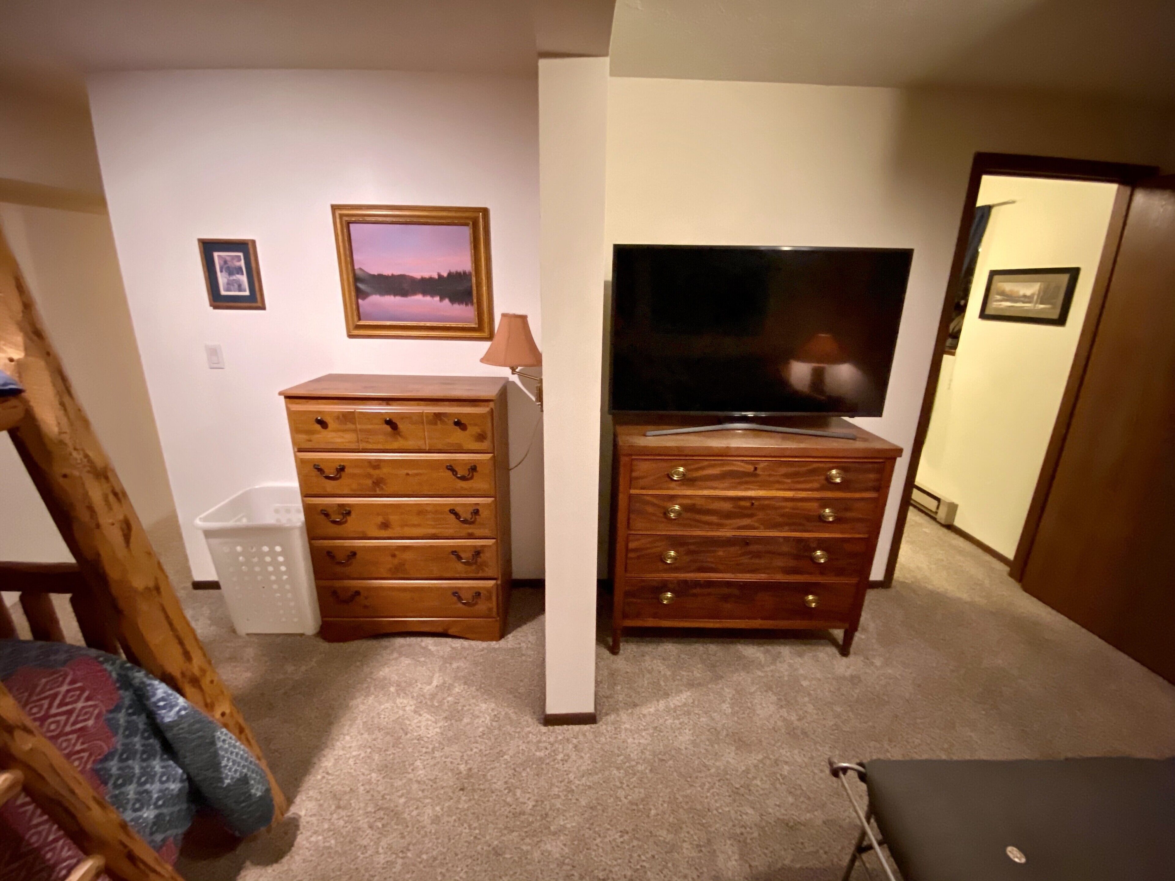 Una habitación con un aparador de madera, un televisor, un cuadro en la pared y una puerta.
