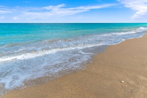 A beach with clear turquoise water and a sandy shore.