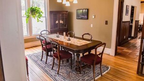 A dining area with a wooden table, six chairs, a chandelier, a cabinet, and a hanging plant. - Your Beautiful Victorian Getaway (Bethel)
