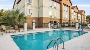 A swimming pool with a no swimming sign, lounge chairs, and a building with multiple windows and balconies. - Clarion Pointe Savannah Gateway I-95 (Savannah)
