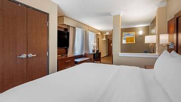 A hotel room with a large bed, a desk, a chair, a wardrobe, and a mirror.