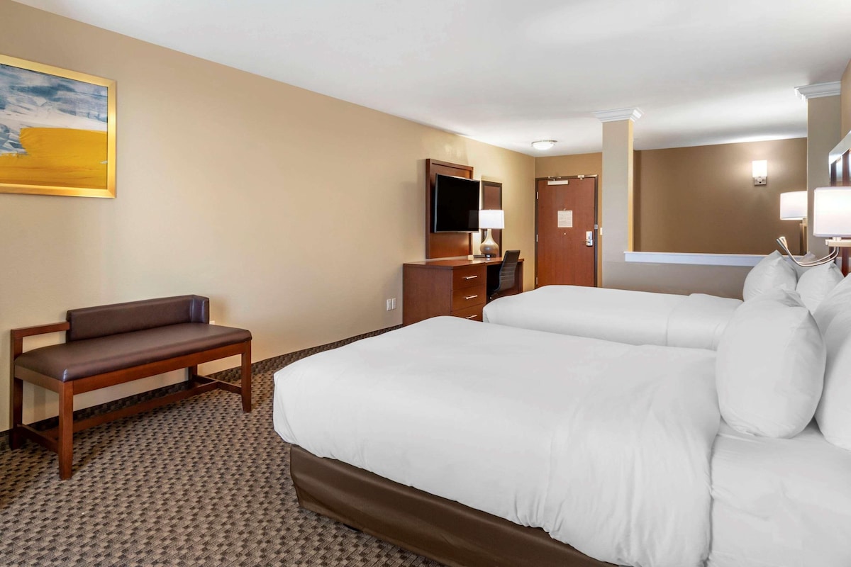 A hotel room with a large bed, a desk, a chair, a TV, and a painting on the wall.