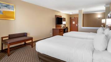 A hotel room with a large bed, a desk with a chair, a television, and a painting on the wall.