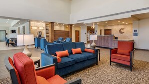 A hotel lobby with a blue sofa, orange armchairs, a reception desk, and a patterned carpet. - Comfort Suites Broomfield-Boulder/Interlocken (Broomfield)