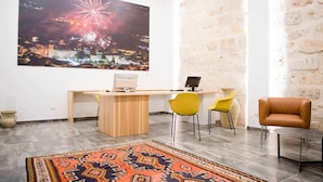A modern room with a wooden desk, two yellow chairs, a brown leather chair, a patterned rug, and a large cityscape artwork on the wall. - Rosa Fresca Aulentissima (Alcamo)