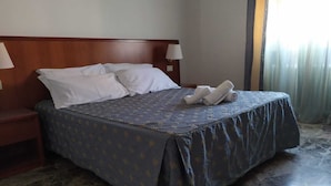 A hotel room with a large bed, two nightstands, a wooden headboard, and a window with curtains. - Bed & Breakfast Domus Cesena (Cesena)