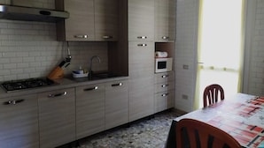 A kitchen with grey cabinets, a gas stove, a microwave, and a sink. - Bed & Breakfast Domus Cesena (Cesena)