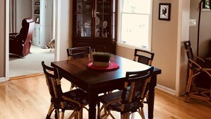 A dining area with a wooden table and wicker chairs, a dark wooden cabinet with glass doors, and a window with natural light. - HOT TUB Columbus Indiana  (Columbus)