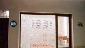 L’entrée d’un hôtel, avec une grande porte en verre sur laquelle le mot « vacances » est répété à plusieurs reprises.