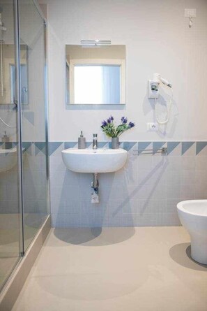 A modern bathroom with a glass shower enclosure, a white sink with a mirror above it, and a toilet to the right. - Cielo D'Alcamo center - Jester (Alcamo)