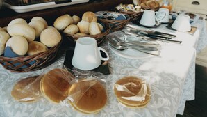 Un bufé de desayuno con panes, bollería y tortitas.
