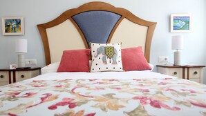 A neatly made bed with a floral bedspread, two red pillows, and a decorative pillow with an elephant design. - Villalbeja Casa Rural (Villalba de la Sierra)