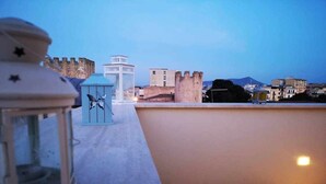 A rooftop terrace with a white lantern, a small table, and a view of a castle-like structure in the background. - Cielo D'Alcamo center - Cielo (Alcamo)