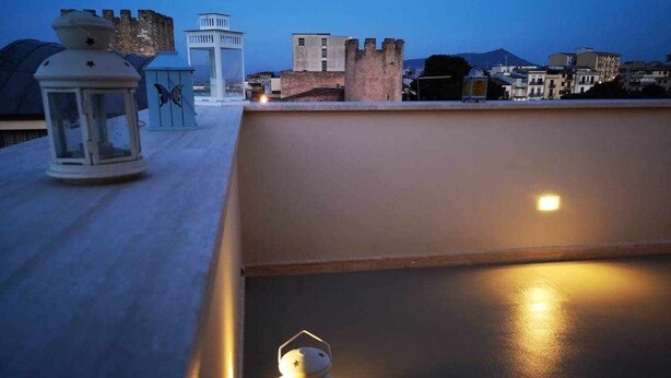 A rooftop terrace with a lantern, a decorative lantern, and a view of a castle-like structure in the background. - Cielo D'Alcamo center - Cielo (Alcamo)