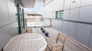 A wooden table and chairs on a balcony with potted plants. - Steep Holm - With Spacious Balcony (Poole)