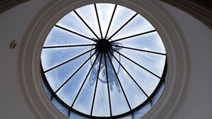 A skylight with a radial design, a circular window with a central support, and a reflection of a tree on the ceiling. - NorteSoul Mouzinho (Porto)
