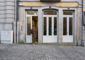 A building with a large arched entrance, two doors, and a tiled facade. - NorteSoul Mouzinho (Porto)