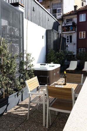 Une terrasse extérieure avec un jacuzzi, des chaises en bois et une table.