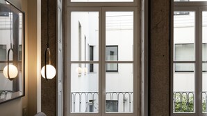 A hotel room with a large bed, a view of the outside balcony, and a door leading to another room. - NorteSoul Mouzinho (Porto)