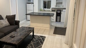 Un espacio habitable compacto con kitchenette, un sofá y una mesa de centro.