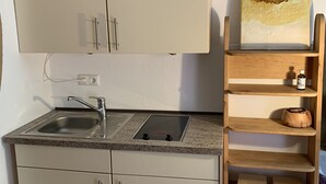Una cocina compacta con microondas, lavamanos y estantes de madera.
