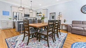 A modern kitchen with white cabinets, stainless steel appliances, and a wooden dining table with six chairs.