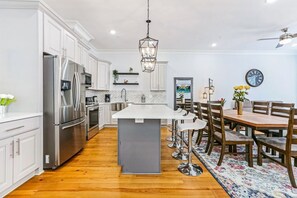 A modern kitchen with white cabinetry, stainless steel appliances, and a central island.