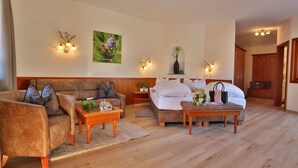Ein gemütliches Wohnzimmer mit einer Couch, einem Couchtisch und einem Bett. Es gibt Wandleuchten und ein Bild an der Wand.