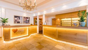 Ein Hotel-Empfangsbereich mit einem Holzbüro, einer Chandelierleuchtre und einer Wand mit gerahmten Bildern.