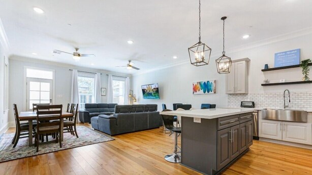 Cocina moderna con una isla central, muebles blancos y pileta de acero inoxidable.