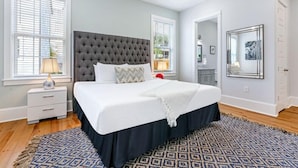Ein Schlafzimmer mit einem großen Bett, weißer Bettwäsche, einem dunklen Kopfteil und einem gemusterten Teppich.