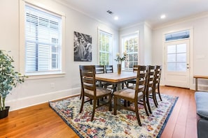 Un coin repas avec une table et des chaises en bois, un tapis coloré et une plante en pot.