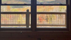 Une pièce dotée de deux fenêtres donnant sur un paysage montagneux aux couleurs automnales.