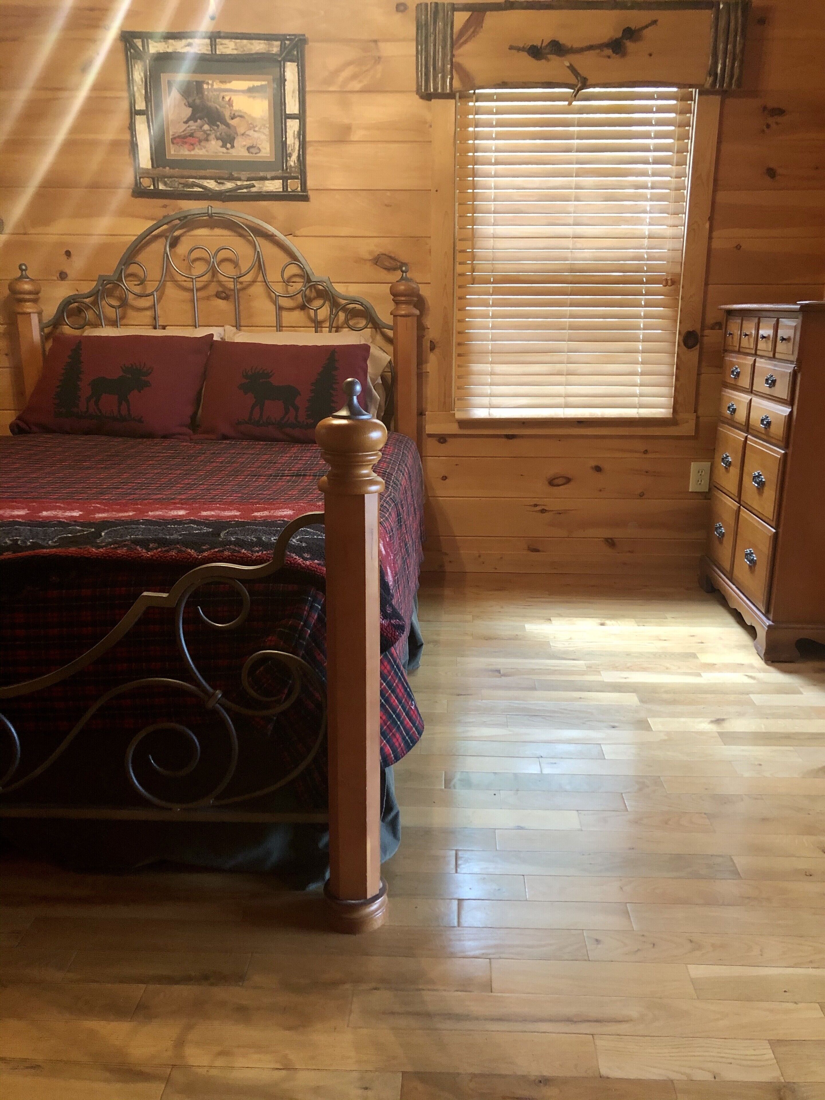 Ein Zimmer aus Holz mit einem Bett, einem Schminktisch und einem Fenster mit Jalousien.