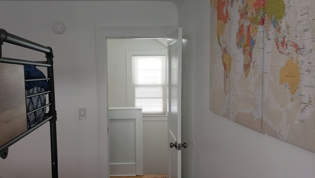 A room with a bunk bed, a white door, and a world map on the wall.