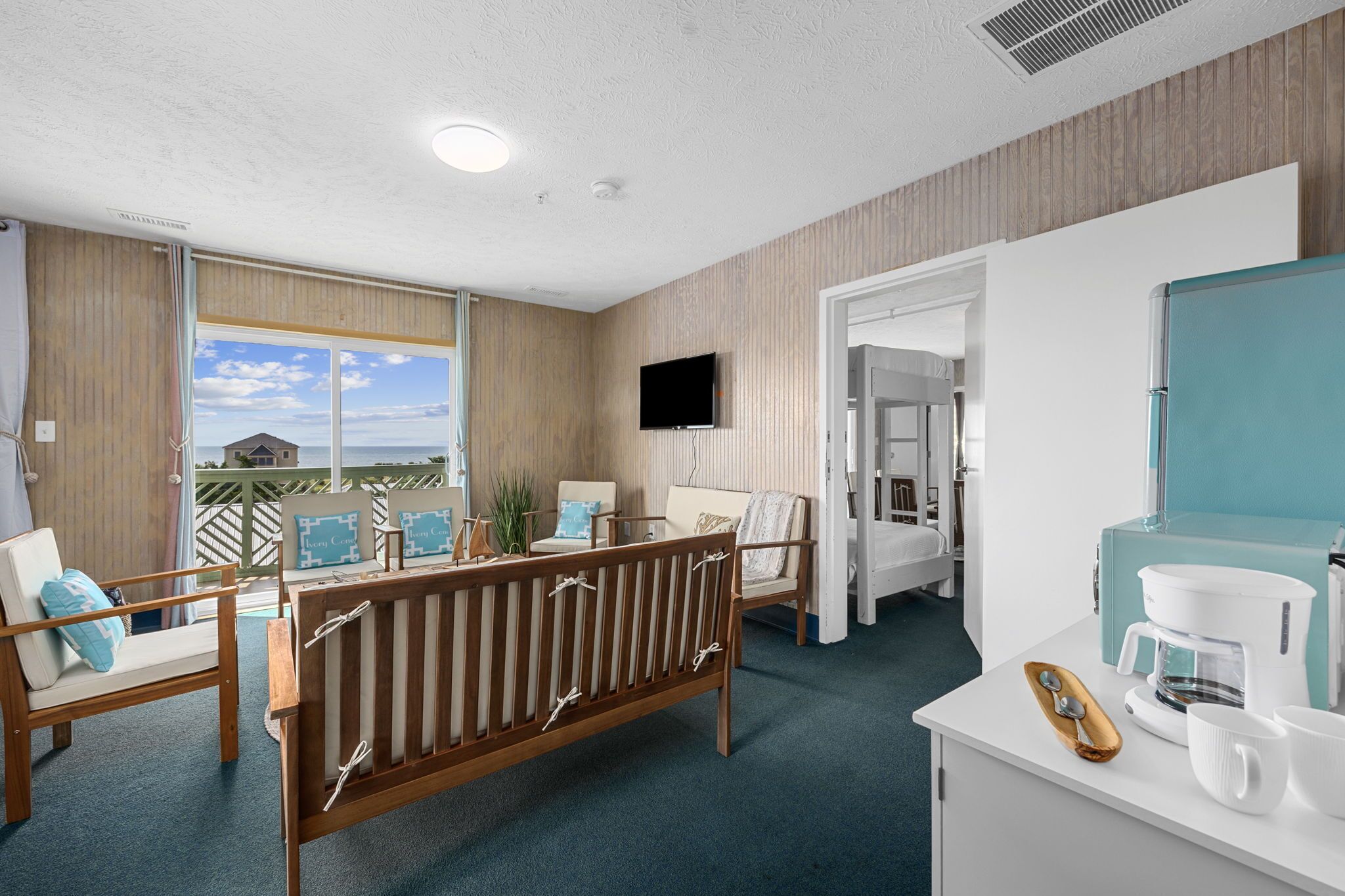 Una habitación de hotel con balcón, televisión, cafetera y cama.