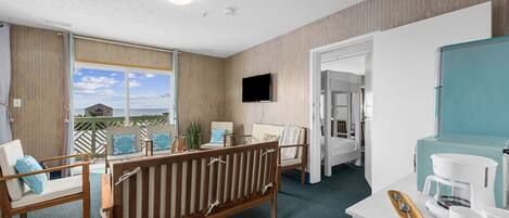 Una habitación de hotel con balcón, televisión, cafetera y cama.