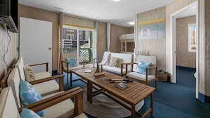 Una habitación con una mesa de madera, dos sofás, una litera y un ventanal grande.