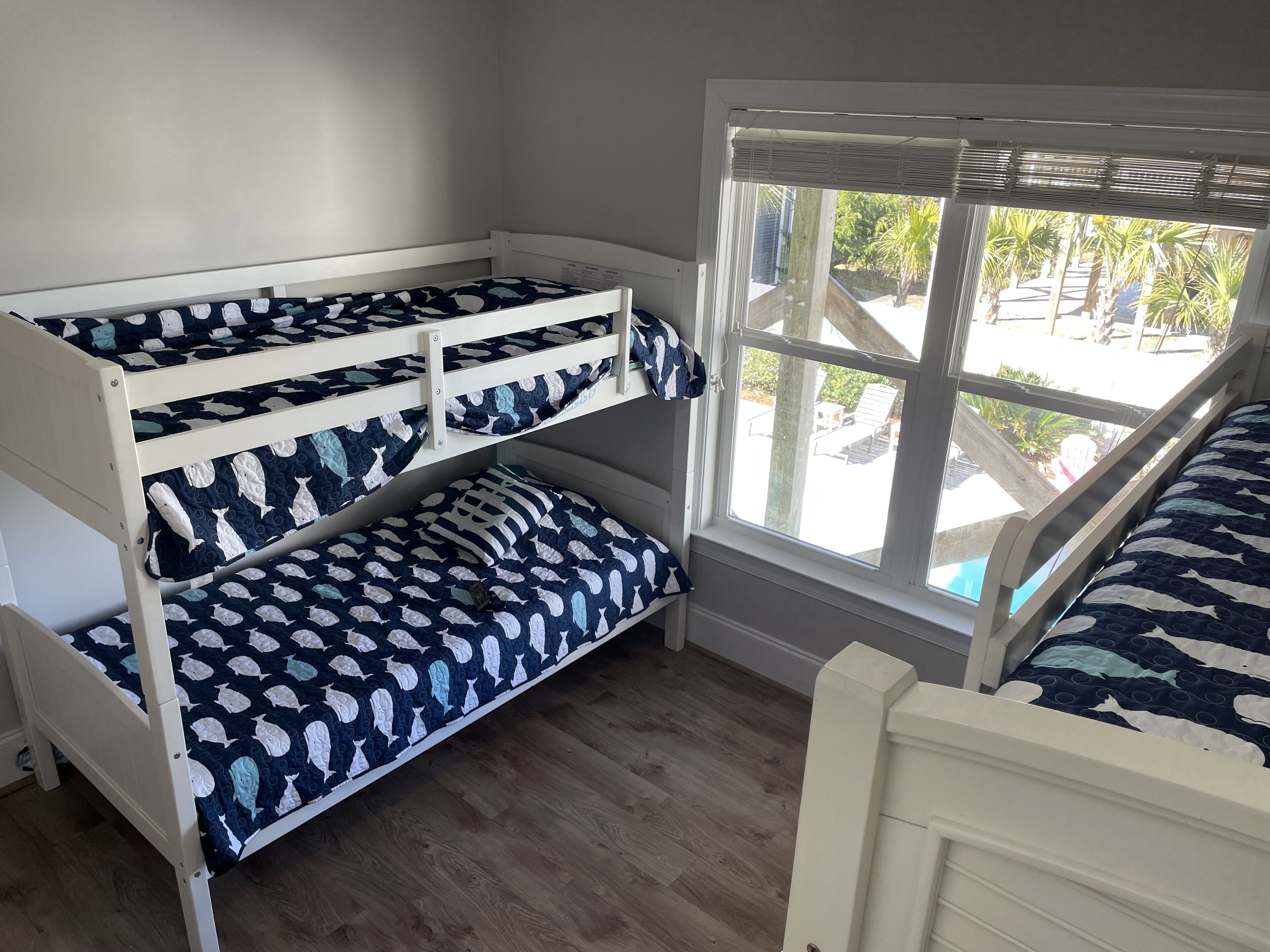 A bunk bed room with a window view of a pool and palm trees.