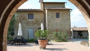 A stone building with a tiled roof, a patio with a table and chairs, and a potted plant. - Linearis holiday house apt E  (Barberino Val D Elsa (Firenze))