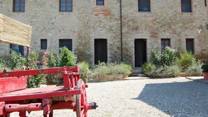 A stone building with multiple windows and a gravel courtyard. - Linearis holiday house apt E  (Barberino Val D Elsa (Firenze))