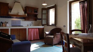 A cozy kitchen with wooden cabinets, a checkered towel, and a wicker chair. - Linearis holiday house apt E  (Barberino Val D Elsa (Firenze))