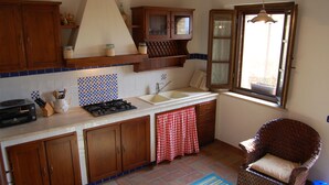 A kitchen with wooden cabinets, a stove, a sink, and a window with curtains. - Linearis holiday house apt E  (Barberino Val D Elsa (Firenze))