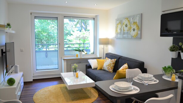 A modern living room with a sofa, coffee table, and dining area. - Cozy and modern apartment in green top location Münst (Münster)