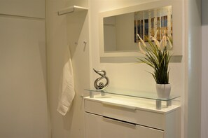 A bathroom with a glass shelf, a mirror, and a towel hanging on a rack.