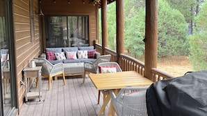 Une terrasse extérieure couverte, dotée d’un plancher en bois, d’un ensemble de canapés et d’une table.